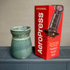 Green ceramic coffee maker next to a red Aeropress box on a gray surface.