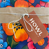 Brown tag with 'HOWL' branding on a colorful floral background